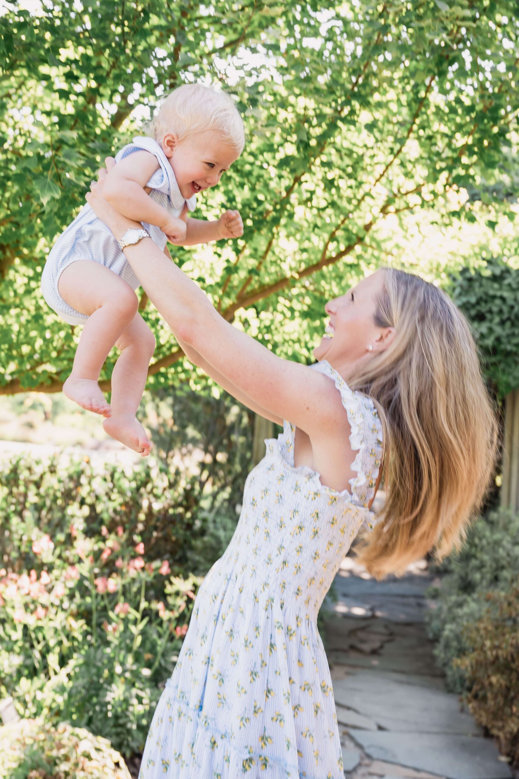 A happy toddler is lifted by mom in a garden path while exploring apex nc parks