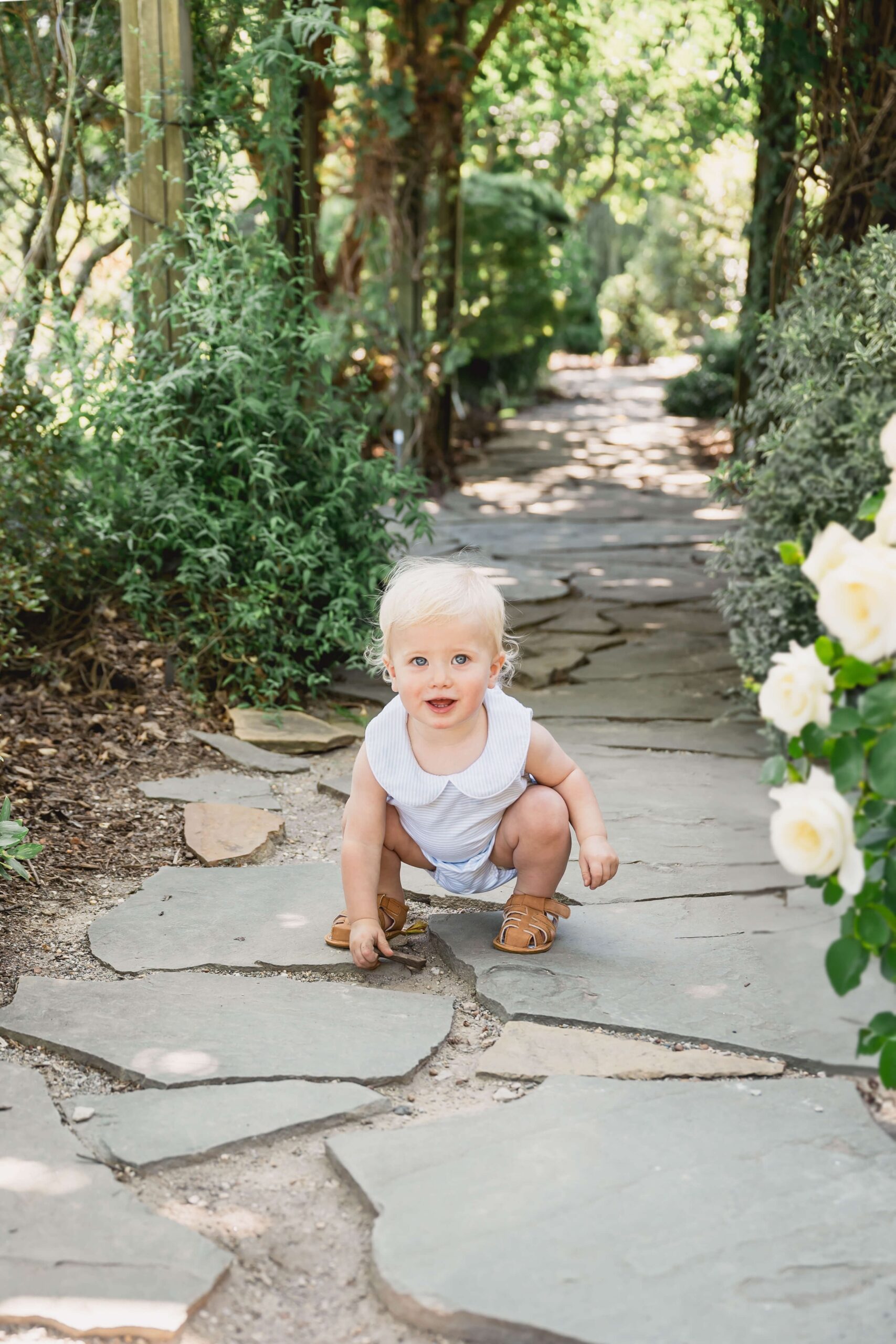 A toddler plays in a garden path paved with stones