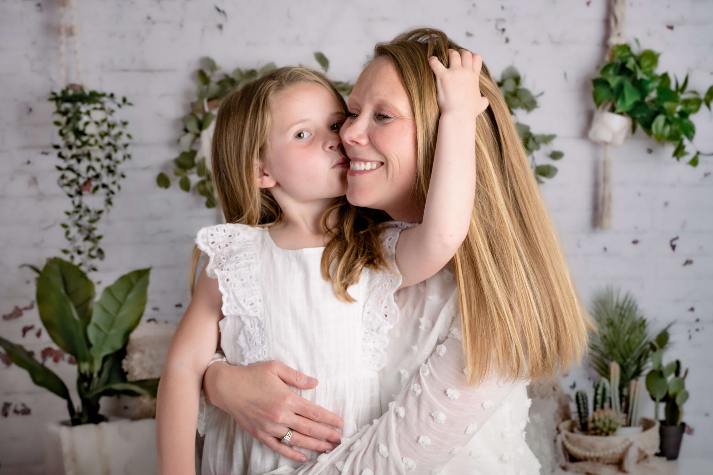 A happy mother hugs her toddler daughter in white dresses before some raleigh summer camps