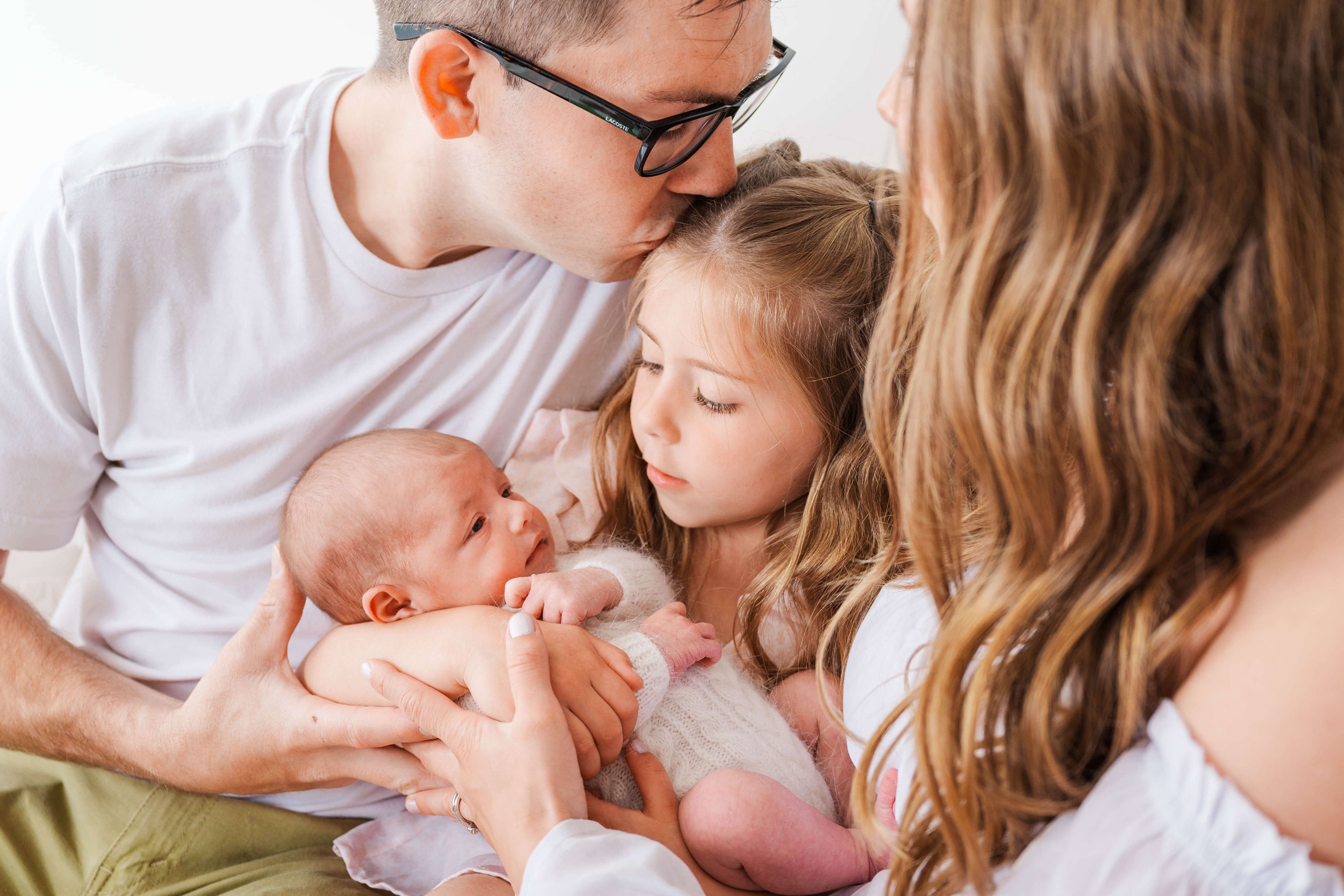 A happy family snuggles while the toddler holds the newborn baby during things to do in raleigh nc